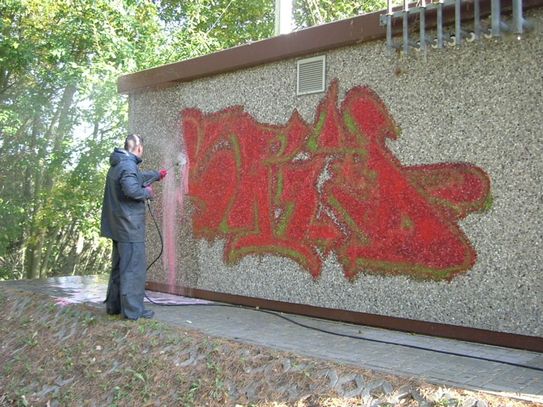 Mann entfernt rotes Graffiti vorher
